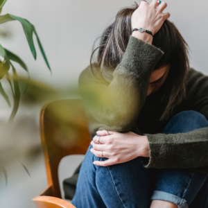A woman sitting with her head in her hands, appearing stressed and overwhelmed. This image represents the emotional challenges of anxiety that can be addressed through counselling in Vancouver.